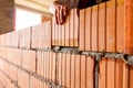 Worker is building wall with red blocks and mortar