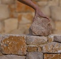 Mason hands working on masonry stone wall Royalty Free Stock Photo