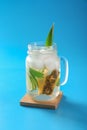 Mason jar with cold pineapple drink on blue background