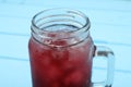 Mason jar of delicious iced hibiscus tea on light blue table, closeup Royalty Free Stock Photo