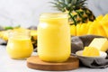 a mason jar filled with bright yellow mango-pineapple smoothie