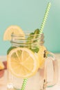 Mason jar glass of homemade lemonade with lemons, mint and green paper straw on wooden rustic background. Summer refreshing Royalty Free Stock Photo