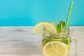 Mason jar glass of homemade lemonade with lemons, mint and paper straw on turquoise background. Summer refreshing beverage Royalty Free Stock Photo