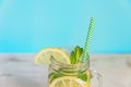 Mason jar glass of homemade lemonade with lemons, mint and paper straw on turquoise background. Summer refreshing beverage Royalty Free Stock Photo