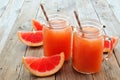 Mason jar glasses of grapefruit juice on rustic wood background Royalty Free Stock Photo