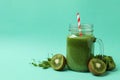 Mason jar with green smoothie and ingredients on mint background