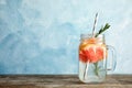 Mason jar of infused water with grapefruit slices on table against color background