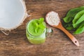 Mason jar mugs filled with green spinach, banana and coconut milk health smoothie with with a spoon of oatmeal on wooden rustic ta Royalty Free Stock Photo