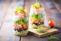 mason jar pasta salads, layered ingredients, on wooden background Royalty Free Stock Photo