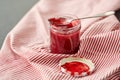 Mason jar with raspberry jam and spoon on towel Royalty Free Stock Photo
