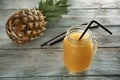 Mason jar of tasty orange smoothie and fresh pineapple on wooden table