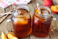 Mason jars of homemade peach iced tea on rustic wood