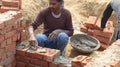 A mason is joining brick with cement to create a wall.