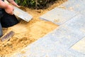 The mason lays gravel slabs on sand to make an alley