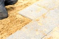 The mason lays gravel slabs on sand to make an alley