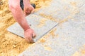 The mason lays gravel slabs on sand to make an alley