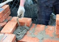 The mason person is laying brick wall applying and smoothing cement with a brick trowel Royalty Free Stock Photo