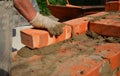 A mason person is laying a brick wall or foundation of a new house. A close-up of a brickwork when a builder is laying a course of Royalty Free Stock Photo