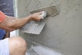 Mason plasters wet cement on the wall with wooden trowel