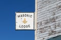 Masonic lodge sign and traditional symbol hanging on side of wooden building