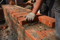 Masonry construction. A mason person, a bricklayer is laying, installing bricks, using a mortar and a trowel, building a brick Royalty Free Stock Photo