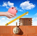 Masonry tools on a brick wall and a hand holding a piggy bank Royalty Free Stock Photo