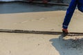 Masonry worker is using long trowel to smooth or leveling concrete flooring work step of the building construction.