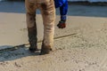 Masonry worker is using long trowel to smooth or leveling concrete flooring work step of the building construction.