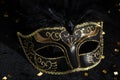 Masquerade gold mask with feathers and confetties on black background