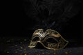 Masquerade gold mask with feathers and confetties on black background