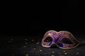 Masquerade mask with confetties on black background