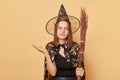 Masquerade party theme. October's magical holiday. Uncertain young woman wizard wearing witch costume holding in hand broom Royalty Free Stock Photo