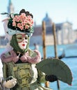 masquerade woman during the Venice carnival in Italy with headdress and fan in hand
