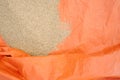 Mass of rice grains poured on a partially folded orange tent to dry up