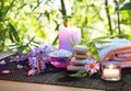 Massage in the bamboo garden with violet flowers, candles and towel