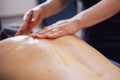 Massage of the cervical collar area with honey. The female client lies on the table and gets a back massage in spa salon or clinic Royalty Free Stock Photo