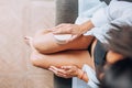 Massage with a dry brush. A girl in a white shirt massages her legs in close-up on a sofa, spa, relaxation, anti-cellulite, Royalty Free Stock Photo