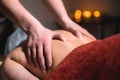 Massage of a female back in a dark room of a spa salon. Male masseur doing massage of the back of the body and lower Royalty Free Stock Photo