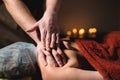 Massage of a female back in a dark room of a spa salon. Male masseur doing massage of the back of the body and lower Royalty Free Stock Photo