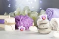 massage stones, burning candles, rolled towels, flowers, abstract lights. Spa resort therapy composition in lilac colors Royalty Free Stock Photo