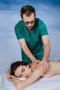 Massage therapist doing massotherapy of a young woman, elbow joint massage. Beautiful relaxed face of a young woman Royalty Free Stock Photo