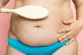 Massage woman large belly with brush closeup, folds on stomach, loose skin and cellulite. Naked overweight plus size