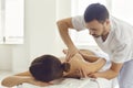 Massagist or manual therapist massaging woman& x27;s shoulder, easing her pain and relaxing her muscles