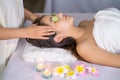 Massesuse put sliced cucumber on eyes of Asian woman and also massage head to give her relaxation in spa shop Royalty Free Stock Photo