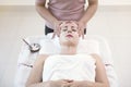 Masseur doing cream mask on face of beautiful young woman relaxing in the spa salon. Royalty Free Stock Photo
