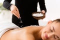 Masseur dropping salt on woman`s back in the spa Royalty Free Stock Photo