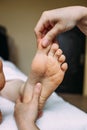 The masseur gives a massage to the female feet at the spa.