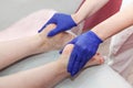 Masseur hands in blue protective gloves touch feet of woman patient doing foot massage procedure in spa salon. Royalty Free Stock Photo