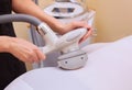 The masseur makes an hardware massage on the patient`s and legs in a white suit, close-up