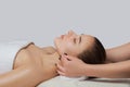 Masseur makes a relaxing massage on the ears, face, neck, shoulders and collarbones of a young beautiful woman in a spa.